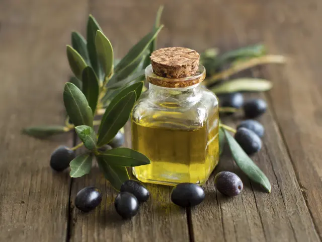 Huile d'olive et olives fraîches sur fond de bois rustique