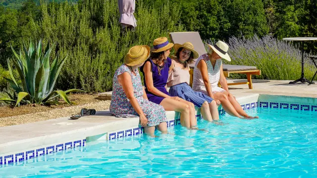 Quatre femmes avec les pieds dans l'eau de la piscine