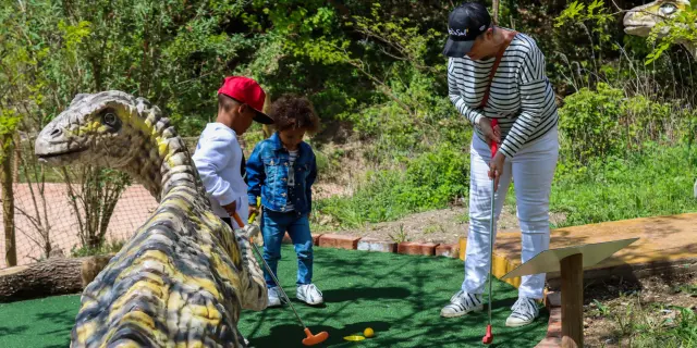 Deux enfants et une personne adulte qui jouent au mini golf