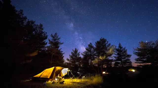 Family tent with rigid steel poles on camping ground under Starry sky with Milky Way